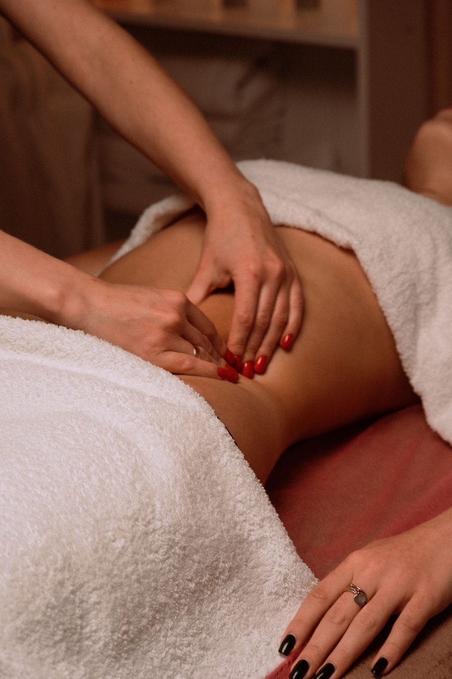 A therapist's hands giving gentle lymphatic drainage massage on a client's abdomen